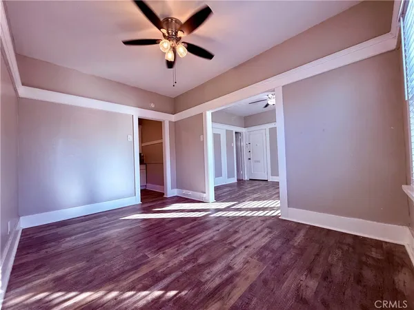 a view of an empty room with window and wooden floor