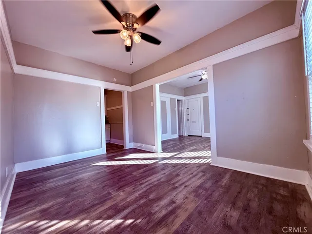 a view of an empty room with window and wooden floor