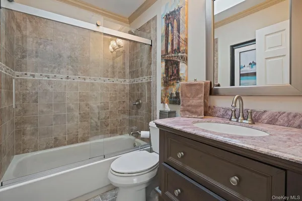 a bathroom with a granite countertop sink a toilet a mirror and bathtub