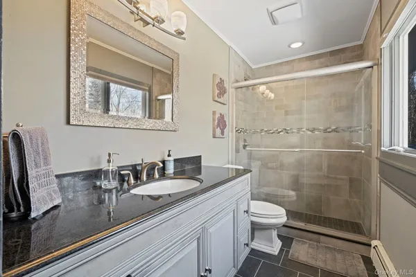 a bathroom with a granite countertop sink a toilet a mirror and shower
