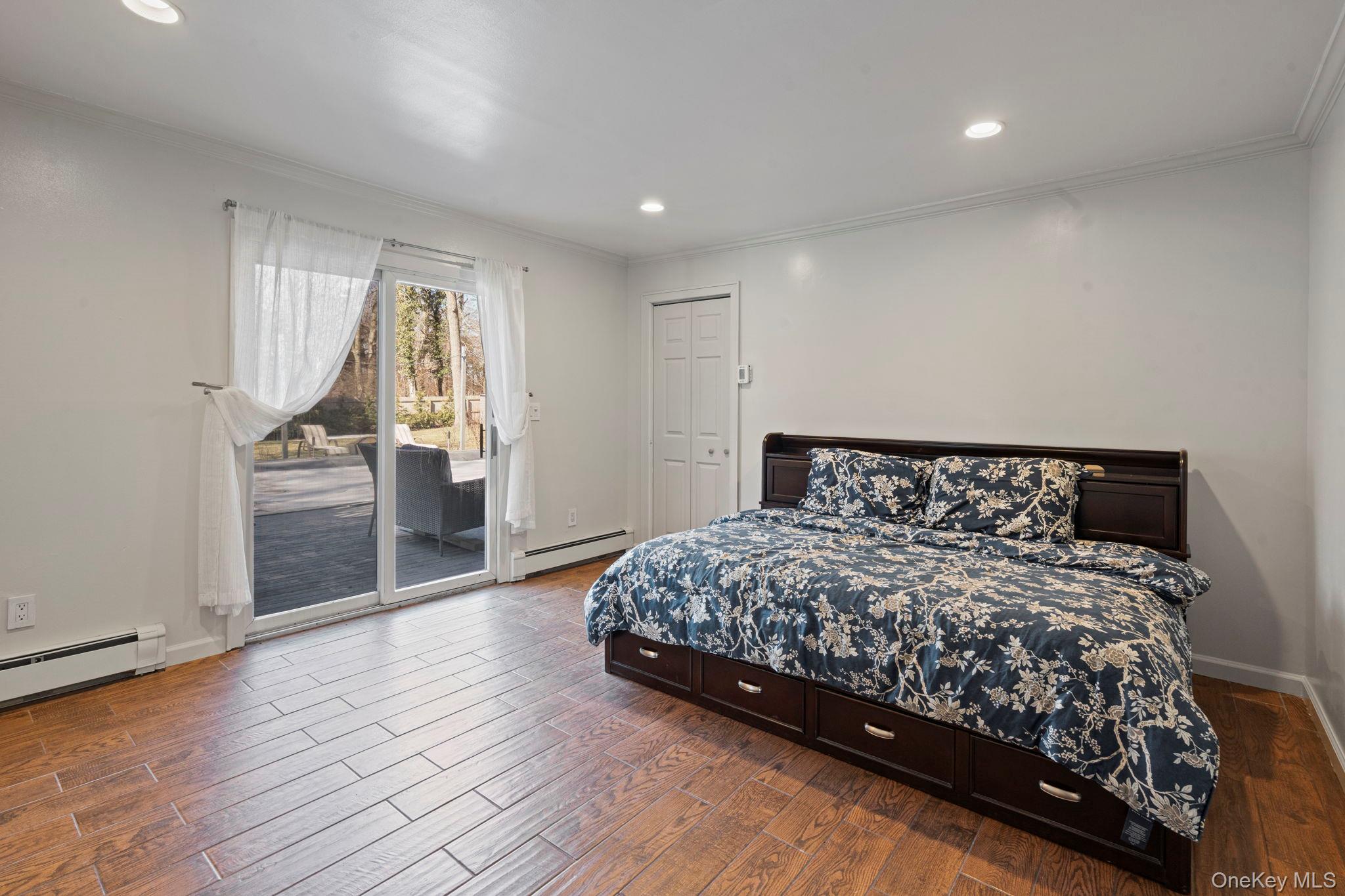 25 Cliff Road West Wading River, NY 11792 - Photo 22 of 35 a large bedroom with a bed and wooden floor