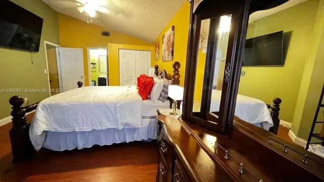 a bedroom with a bed tv and wooden floor