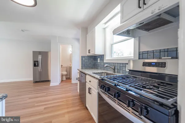 a kitchen with wooden floor a sink and a stove