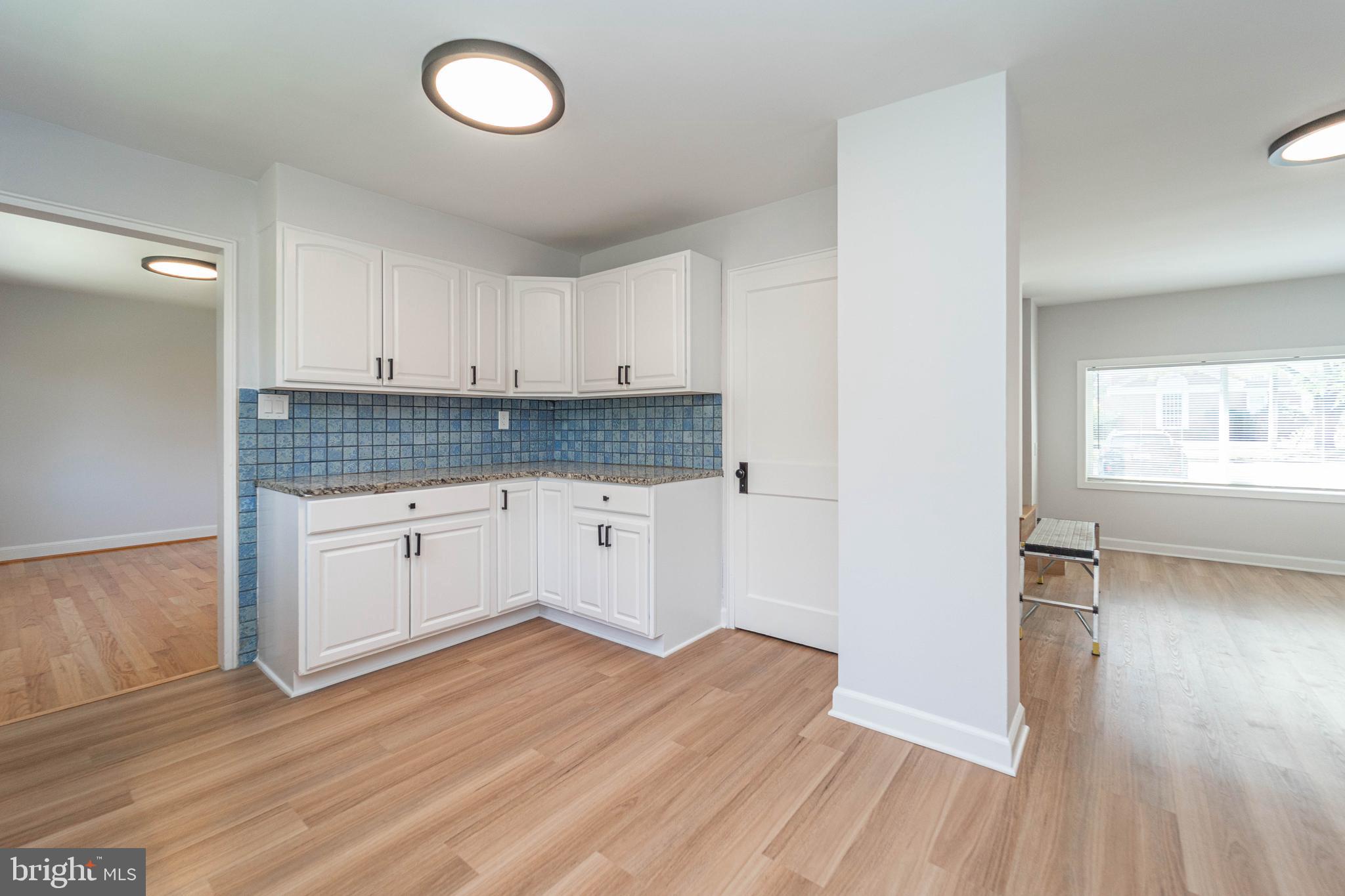 8909 Georgia Avenue Silver Spring, MD 20910 - Photo 20 of 47 a kitchen with granite countertop a stove a sink and white cabinets with wooden floor