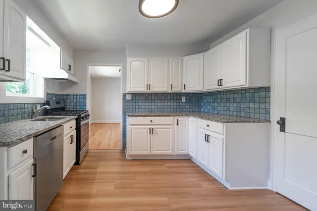 a kitchen with granite countertop a stove sink and cabinets