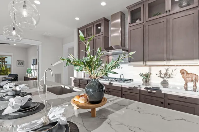 a kitchen that has a lot of cabinets a sink a stove and chairs in it