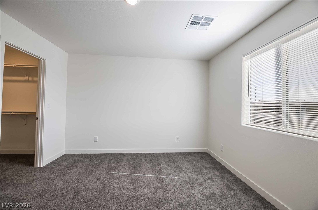 12749 Epperly Street Henderson, NV 89044 - Photo 10 of 22 A well-lit bedroom offering a walk-in closet and soft carpeting for ultimate comfort.