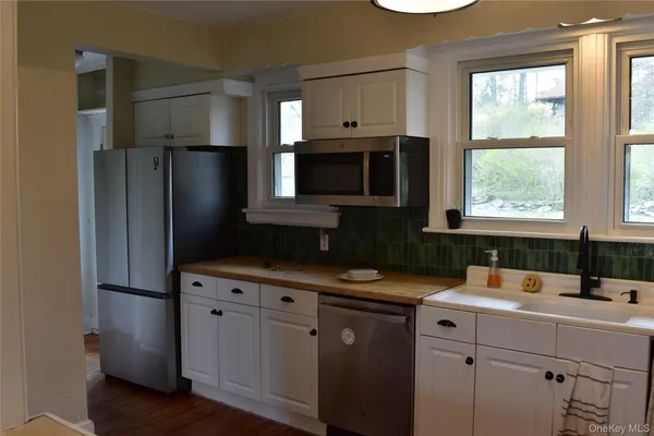 a kitchen with stainless steel appliances a sink a stove a microwave cabinets and wooden floor