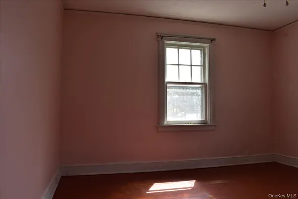 an empty room with wooden floor cabinet and windows