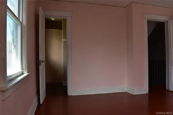 a view of an empty room with wooden floor and windows