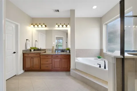 a spacious bathroom with a tub sink shower and mirror
