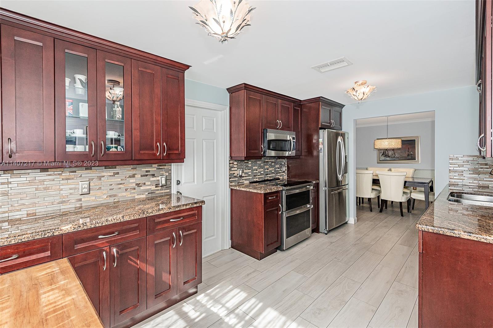 22833 Southwest 65th Way Boca Raton, FL 33428 - Photo 17 of 40 a kitchen with stainless steel appliances kitchen island granite countertop a stove sink and cabinets