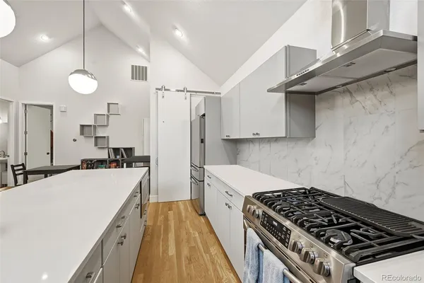 a large kitchen with granite countertop a stove a sink a dining table and chairs with wooden floor
