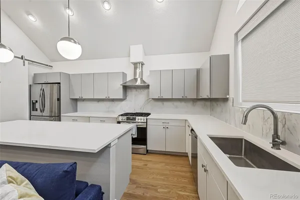 a kitchen with stainless steel appliances a refrigerator a stove a dining table and chairs with wooden floor
