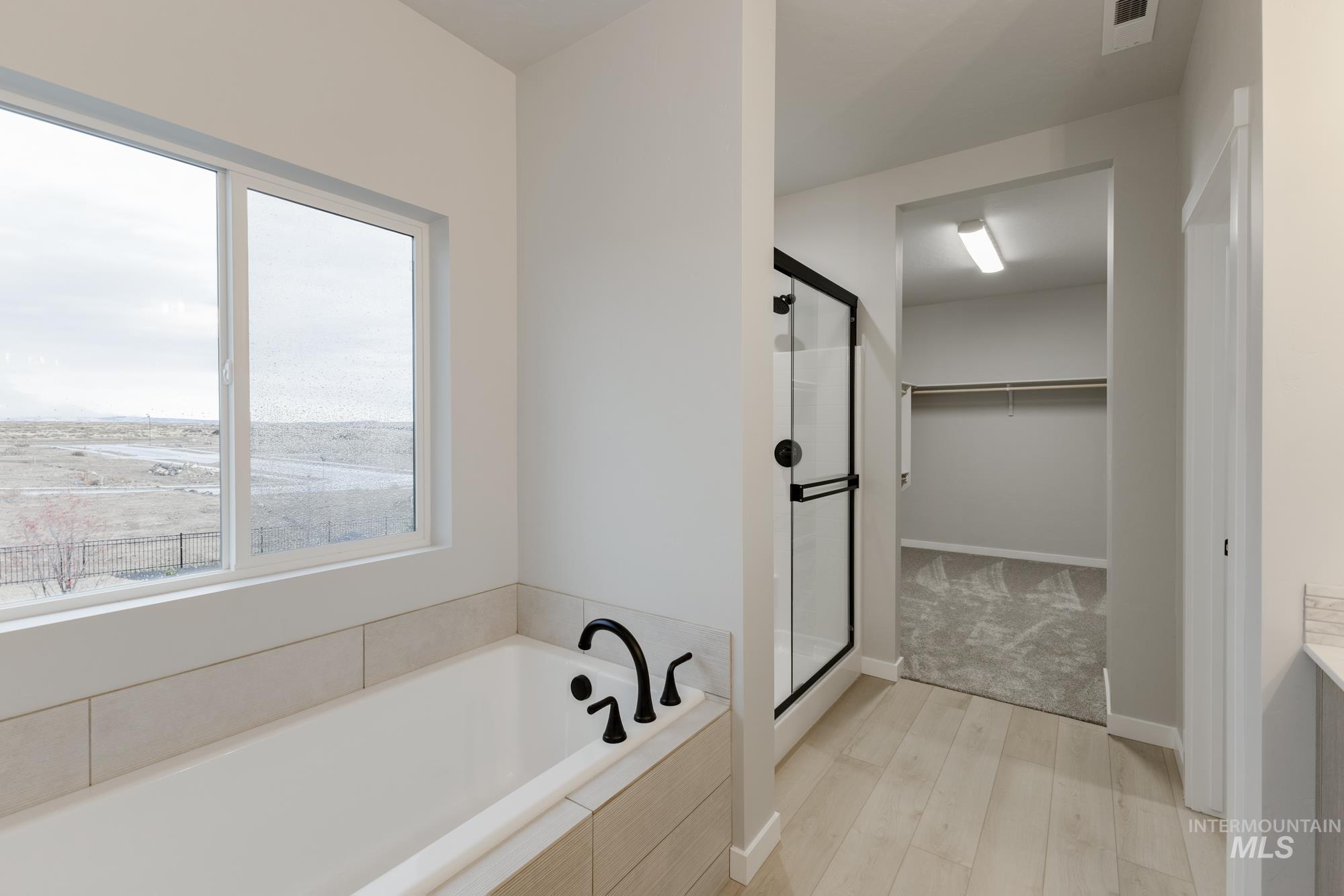 6494 South Sunfish Avenue Boise, ID 83709 - Photo 27 of 32 Full bathroom with a walk in closet, a shower stall, a bath, and light wood finished floors