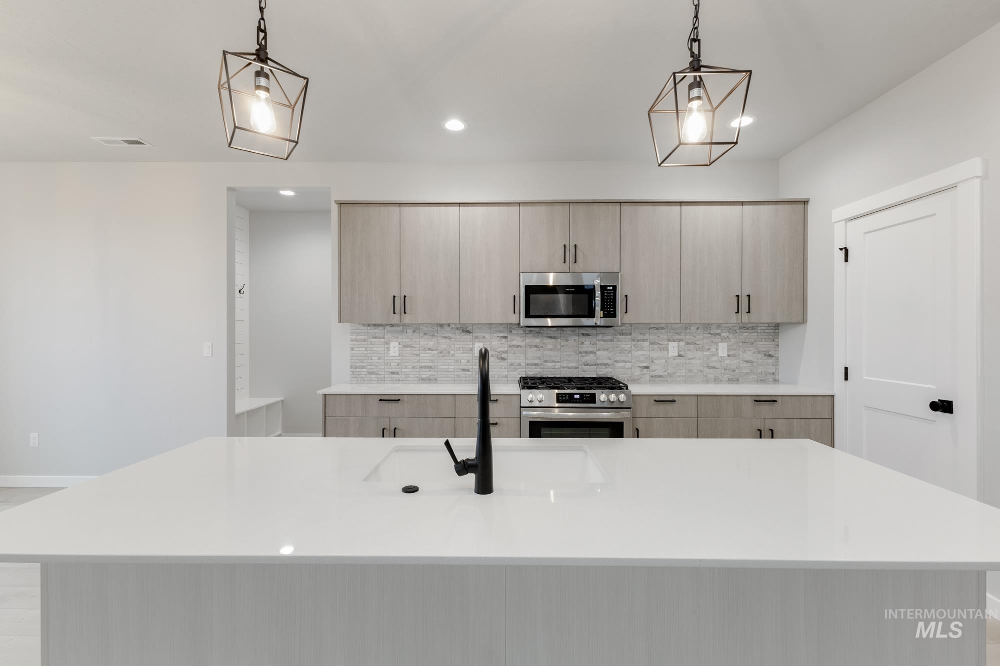 6494 South Sunfish Avenue Boise, ID 83709 - Photo 4 of 32 Kitchen featuring stainless steel appliances, light stone countertops, a kitchen island with sink, light brown cabinetry, and recessed lighting