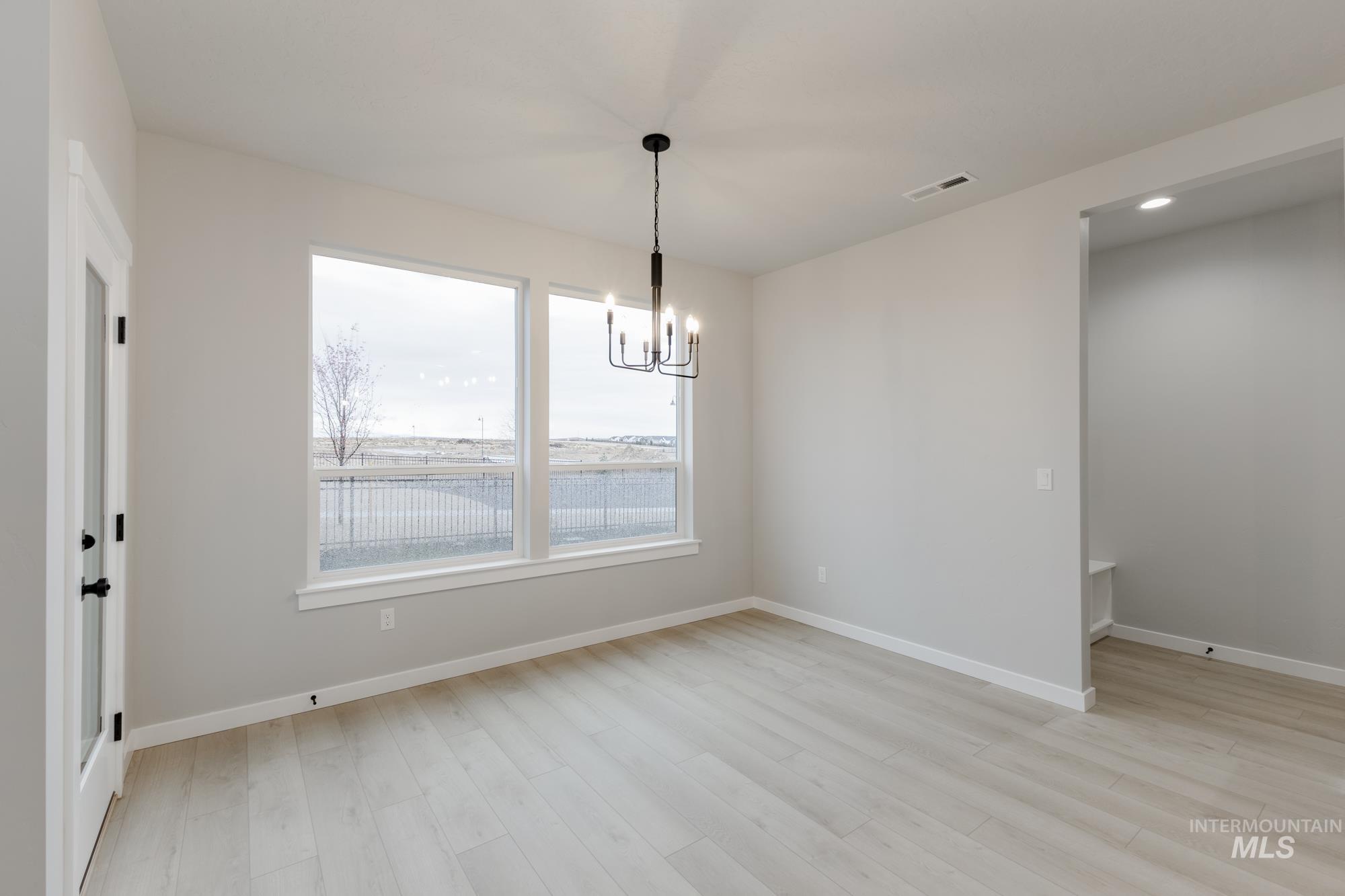 6494 South Sunfish Avenue Boise, ID 83709 - Photo 7 of 32 Unfurnished dining area with a chandelier and light wood-type flooring