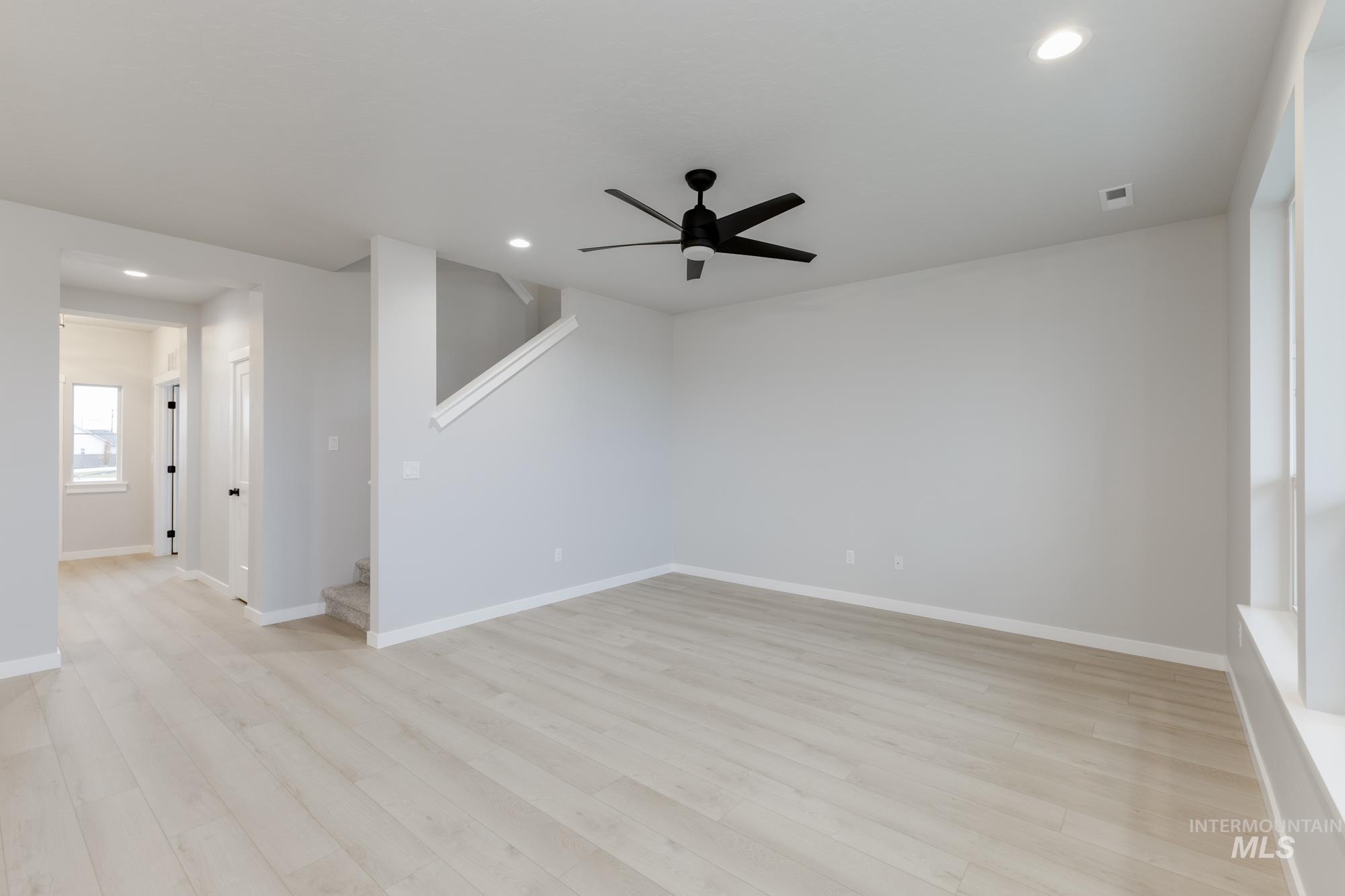 6494 South Sunfish Avenue Boise, ID 83709 - Photo 9 of 32 Unfurnished room with a ceiling fan, light wood-style floors, recessed lighting, and stairway