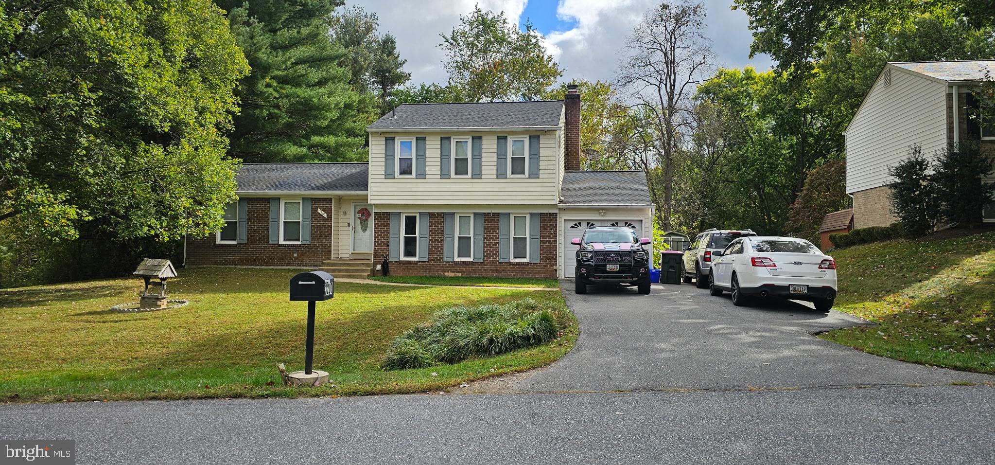 a front view of a house with a garden and trees