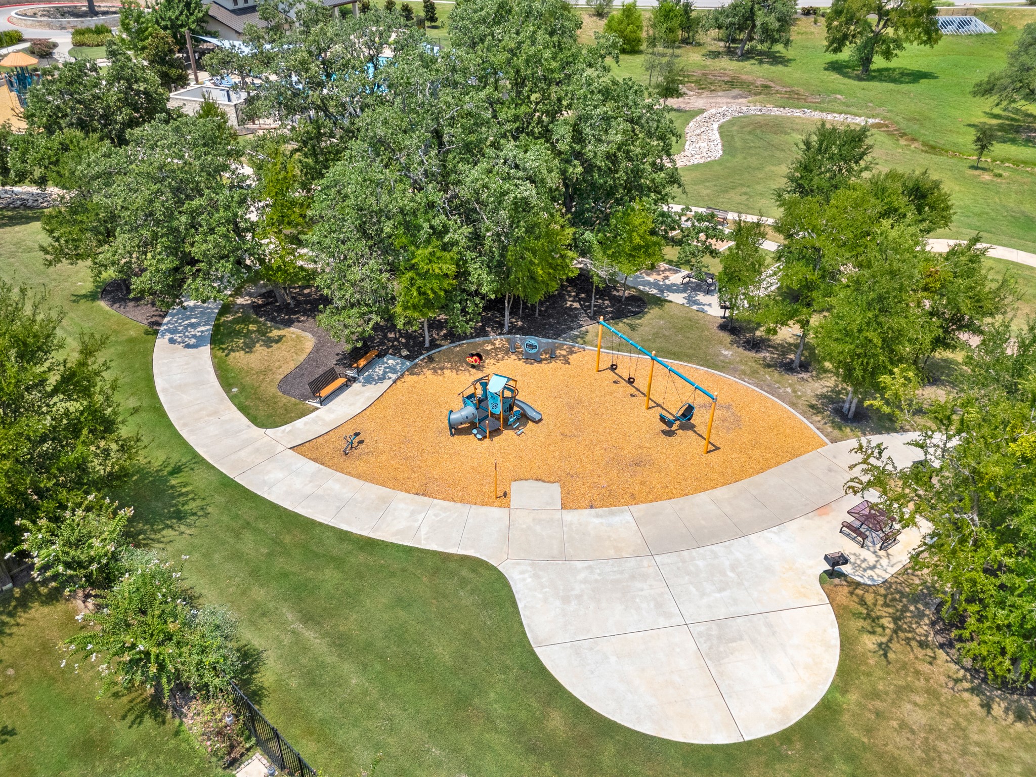 152 Mountain Valley Street Georgetown, TX 78628 - Photo 22 of 38 Paved walking paths wind around a shaded neighborhood playground surrounded by mature trees.