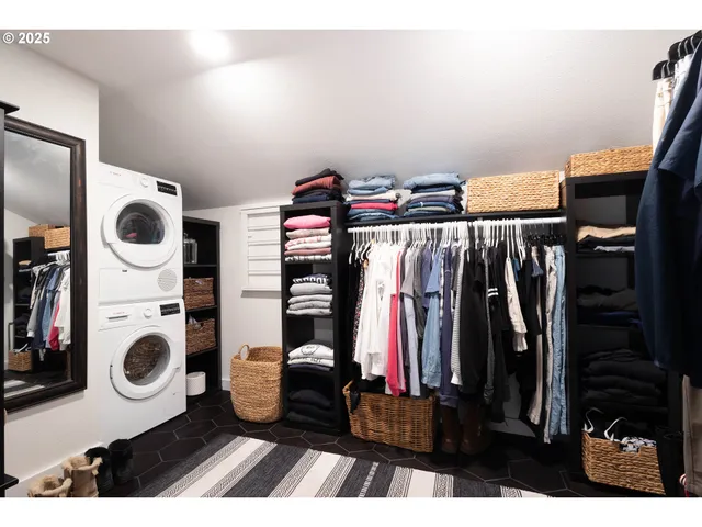 a view of walk in closet with clothes and washer