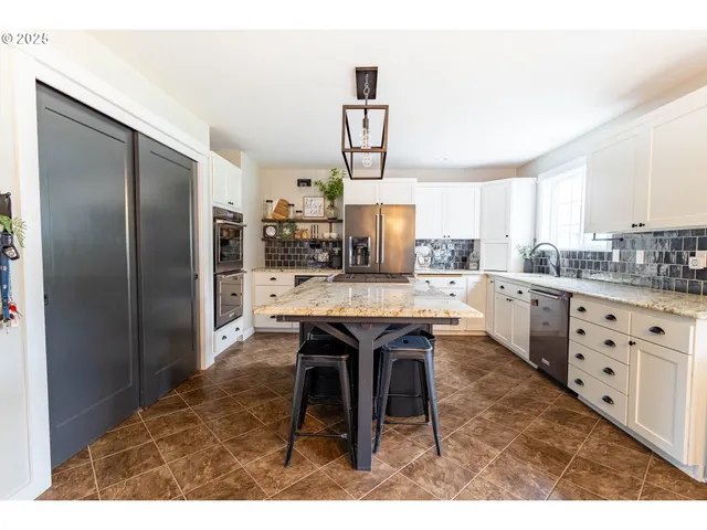 a kitchen with stainless steel appliances kitchen island granite countertop a table chairs a sink and cabinets