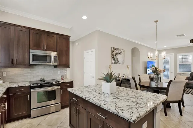 a kitchen with stainless steel appliances kitchen island granite countertop a stove and a white cabinets