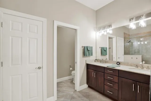 a spacious bathroom with a double vanity sink a large mirror a shower and vanity