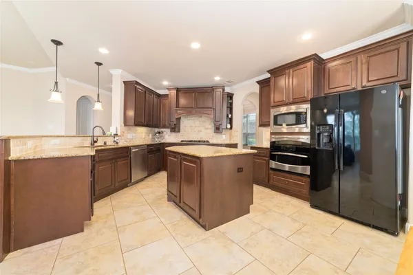 a kitchen with stainless steel appliances granite countertop a stove top oven a refrigerator a sink and dishwasher