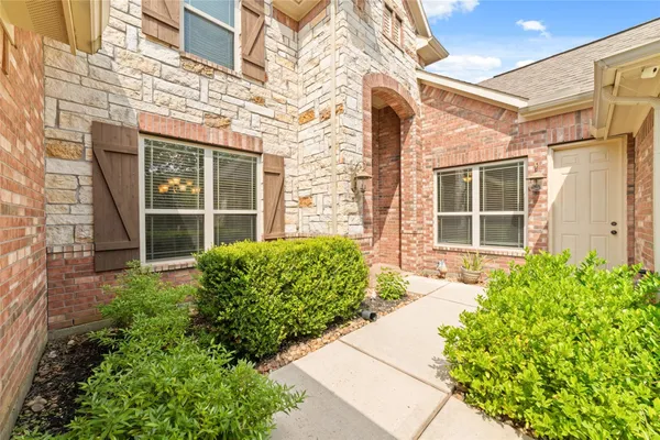 front view of a brick house with a large window and potted plants