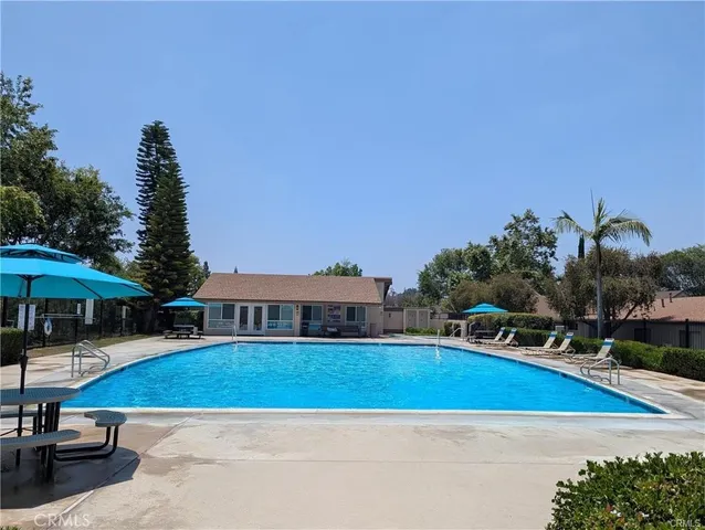 a view of swimming pool with outdoor seating and trees in the background