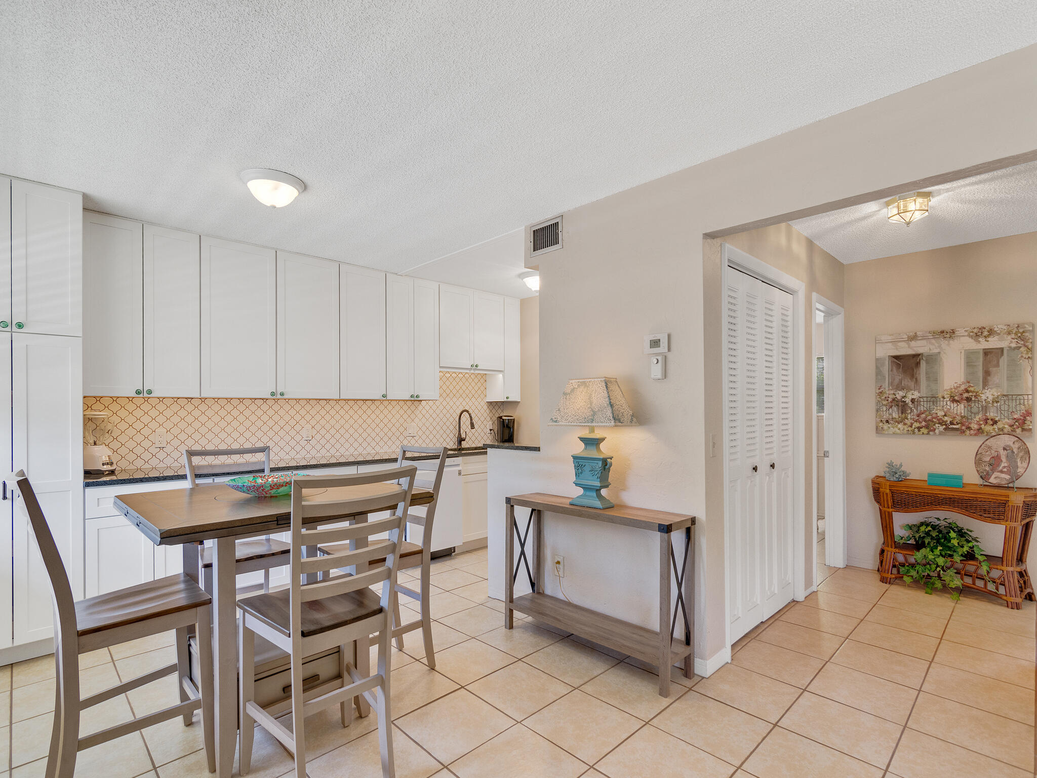 Undisclosed Address Vero Beach, FL 32960 - Photo 10 of 29 a kitchen with a dining table chairs and white cabinets