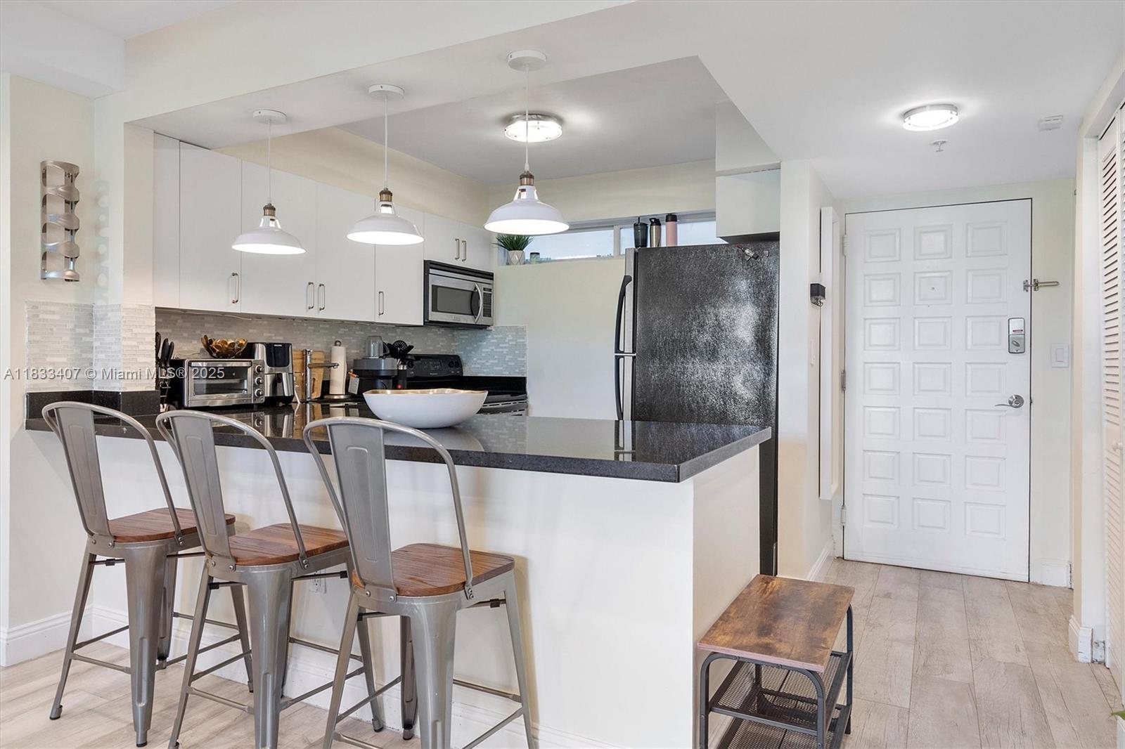 650 Northeast 64th Street, Unit G210 Miami, FL 33138 - Photo 14 of 25 a kitchen with stainless steel appliances kitchen island granite countertop a table and chairs in it