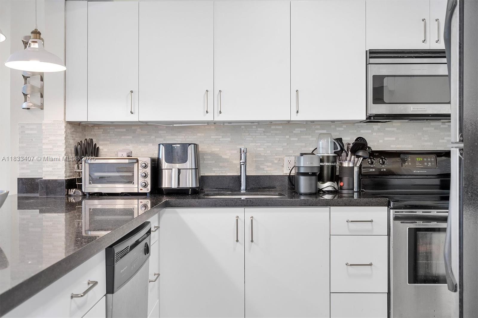 650 Northeast 64th Street, Unit G210 Miami, FL 33138 - Photo 15 of 25 a kitchen with granite countertop a sink and cabinets