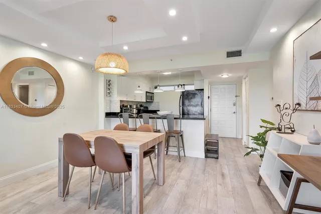a kitchen with stainless steel appliances kitchen island granite countertop a table chairs and a refrigerator