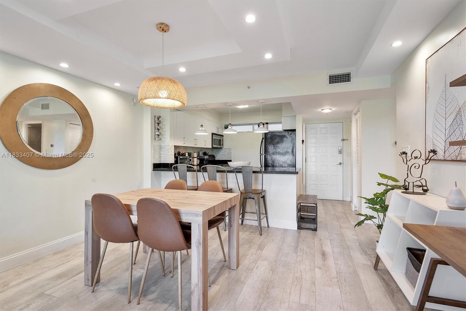 650 Northeast 64th Street, Unit G210 Miami, FL 33138 - Photo 4 of 25 a kitchen with stainless steel appliances kitchen island granite countertop a table chairs and a refrigerator