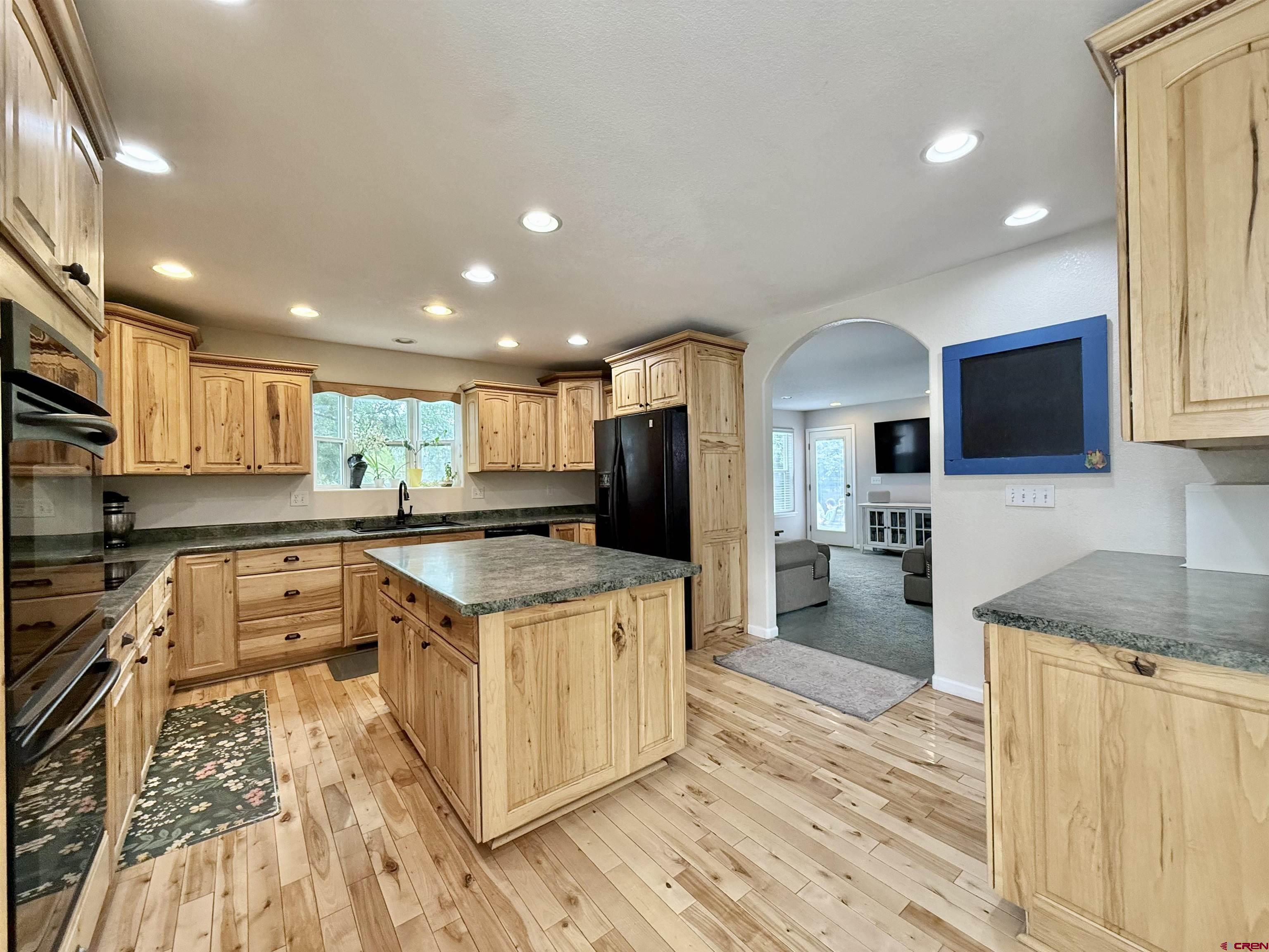 2941 Lost Creek Road North Montrose, CO 81401 - Photo 15 of 45 a kitchen with stainless steel appliances granite countertop a stove top oven a sink dishwasher a refrigerator and white cabinets with wooden floor