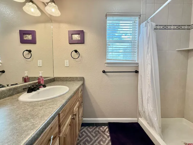 a bathroom with a granite countertop sink a mirror and a shower