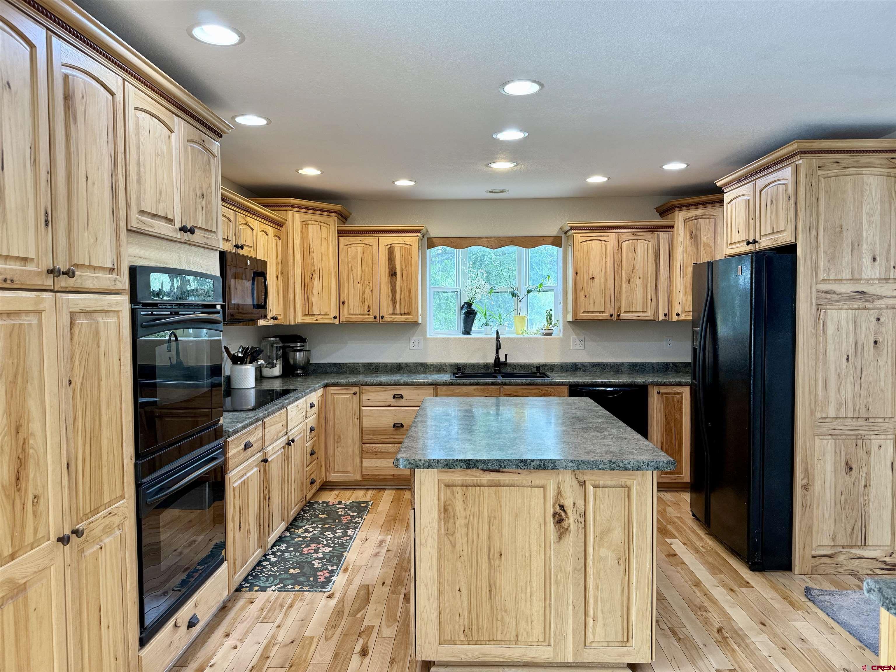 2941 Lost Creek Road North Montrose, CO 81401 - Photo 6 of 45 a kitchen with stainless steel appliances granite countertop a refrigerator a sink dishwasher a stove and white countertops with wooden floor