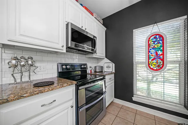 a kitchen with stainless steel appliances granite countertop a kitchen island a stove a table and chairs