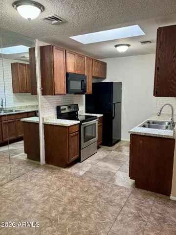 a kitchen with stainless steel appliances granite countertop a stove a sink dishwasher a refrigerator and a microwave oven
