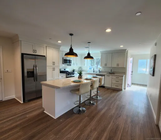 a kitchen with stainless steel appliances kitchen island hardwood floor sink stove refrigerator and cabinets