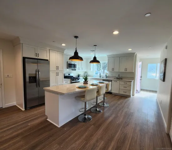 a kitchen with stainless steel appliances kitchen island hardwood floor sink stove refrigerator and cabinets