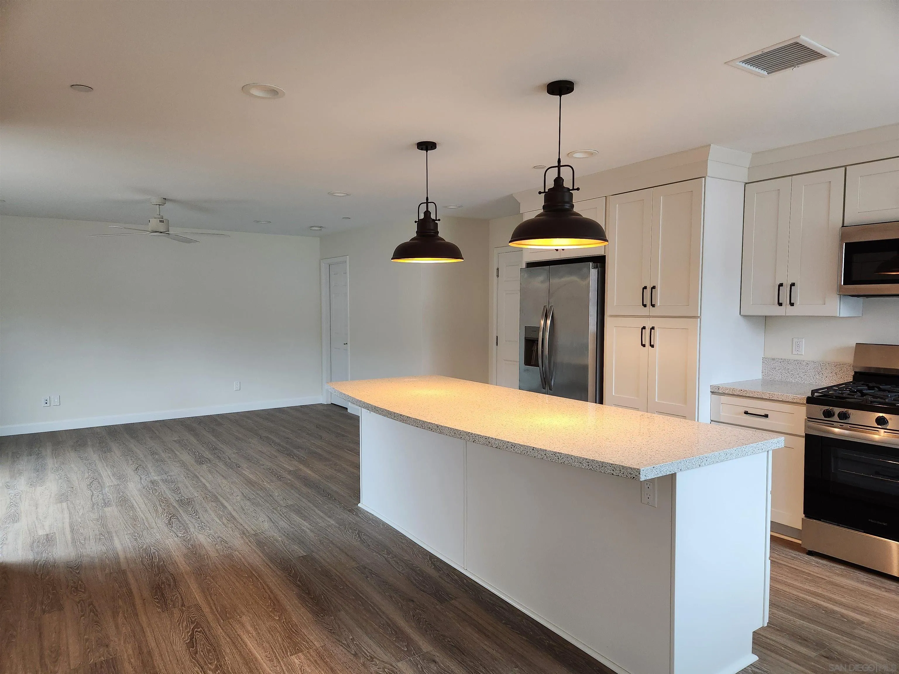 750 North Citrus Avenue, Unit 1 Vista, CA 92084 - Photo 2 of 14 a room with kitchen island a wooden floor and a stove top oven