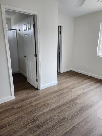 an empty room with wooden floor and mirror