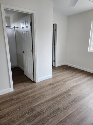 an empty room with wooden floor and mirror