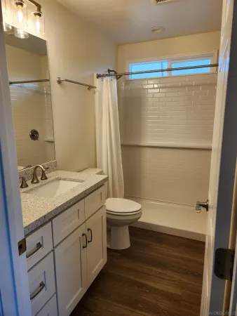 a bathroom with a granite countertop sink toilet and shower