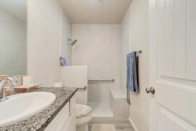 a bathroom with a granite countertop bathtub sink vanity mirror and toilet