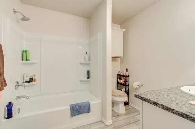 a bathroom with a granite countertop sink a toilet and shower