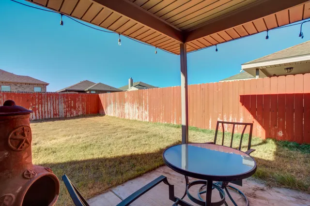 a view of a backyard with table and chairs with wooden fence